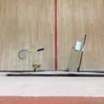 looking down on an open door and squash racquets in a squash court